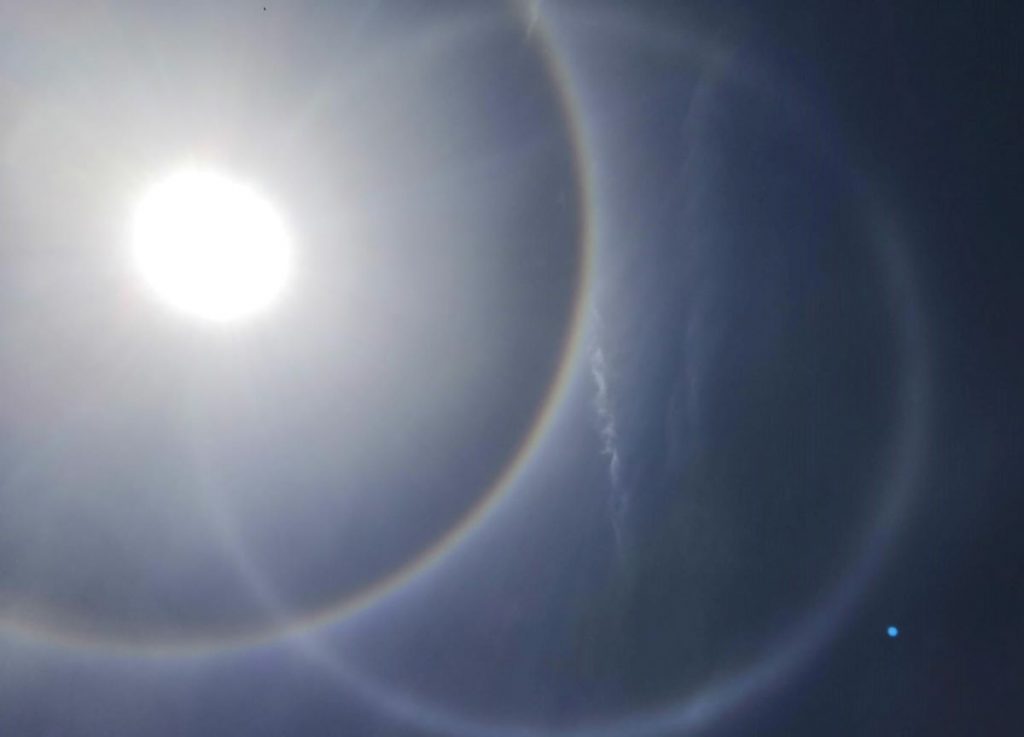 Foto de un halo solar y un círculo parhélico tomada desde Capalbio, Italia